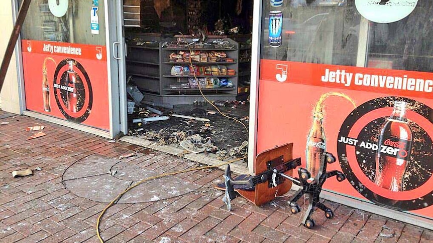 A chair with tape on it lies on the footpath outside a Glenelg convenience store after a fire.