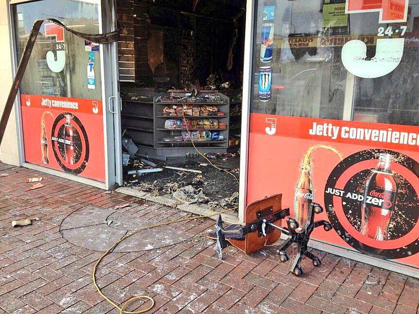 A chair with tape on it lies on the footpath outside a Glenelg convenience store after a fire.