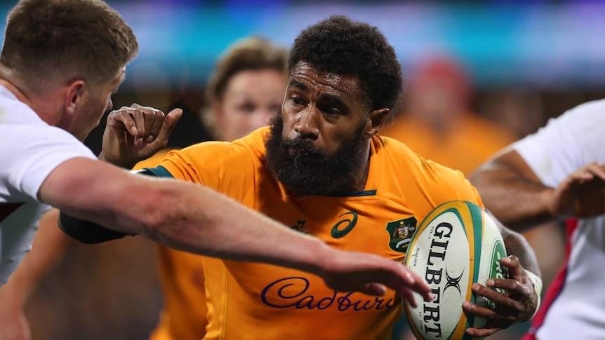 Wallabies' Marika Koroibete raises his arm while running with the ball to fend off an England defender during a rugby union Test