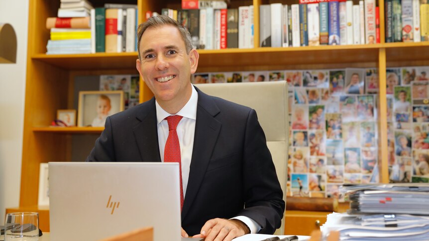 Jim Chalmers smiles while sitting behind a laptop in his parliament house office