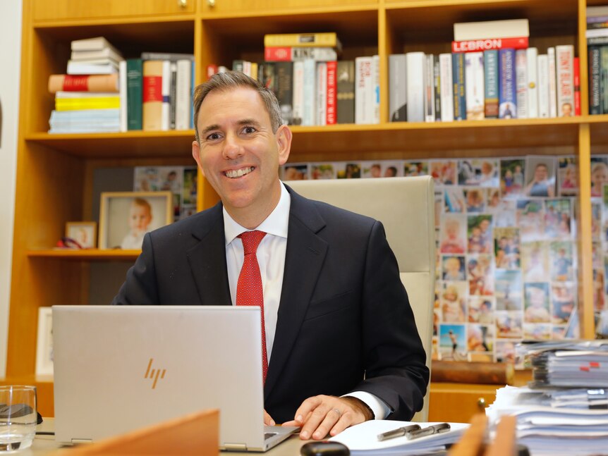 Jim Chalmers smiles while sitting behind a laptop in his parliament house office