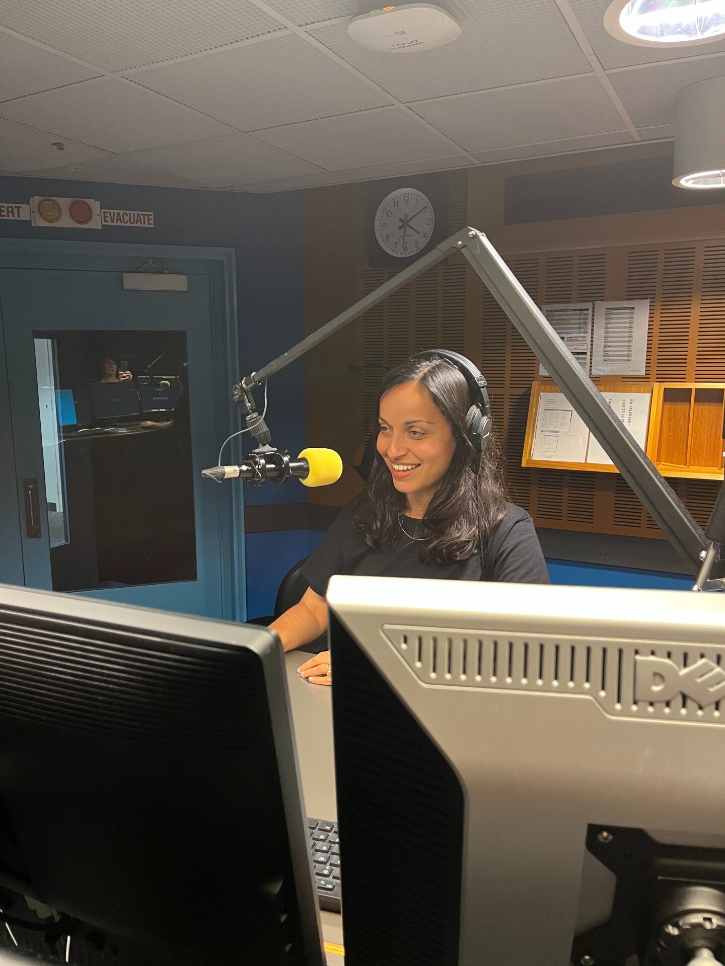 Woman with headphones on talking into a microphone in an audio studio.