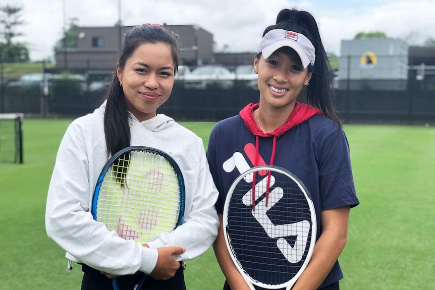 Lizette Cabrera and Priscilla Hon hold tennis racquets on a tennis court in Brisbane.
