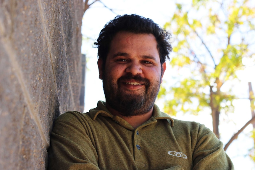 Robert Clayton standing in front of a brick wall and tree.