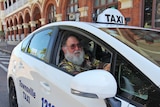 Man with a beard sits behind the wheel of a Townsville Taxi