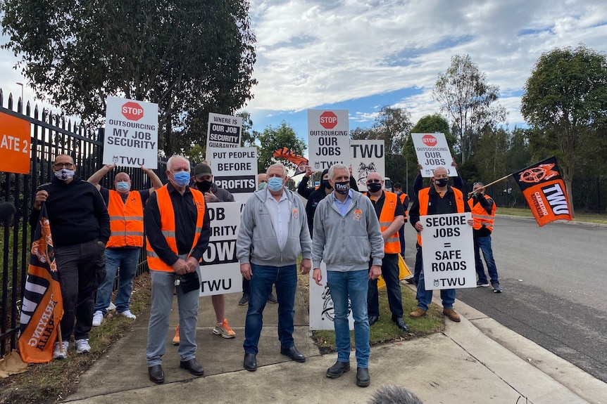 FedEx workers in Sydney rally during a strike, waving placards and flags.