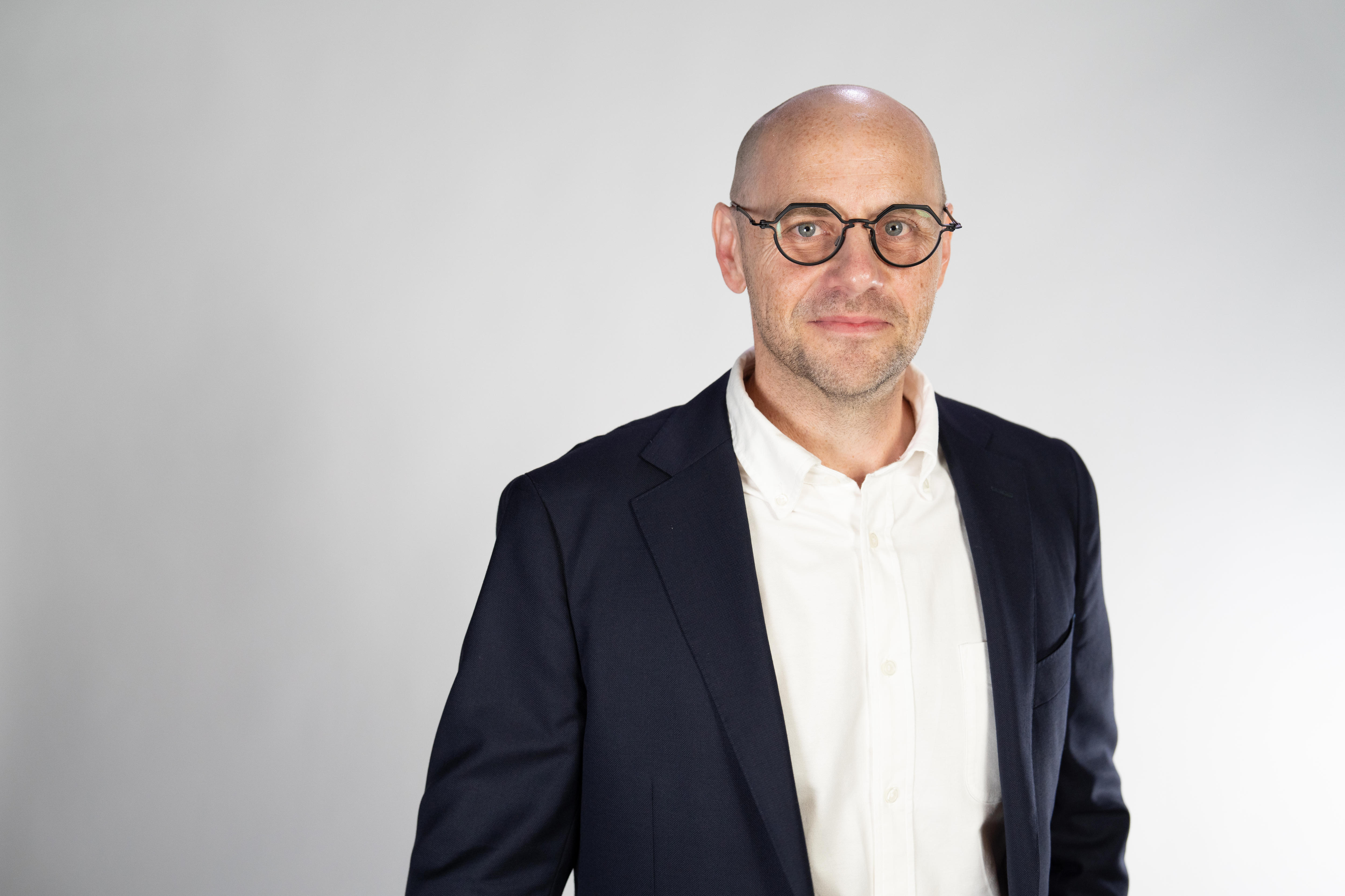Brett Worthington looks at the camera wearing a blue blazer and glasses