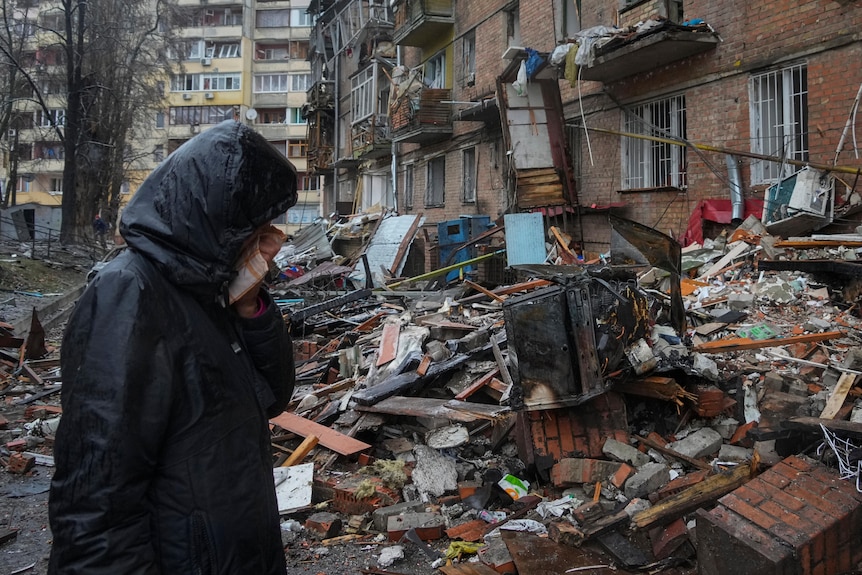 Woman crying outside home damaged in air strikes.