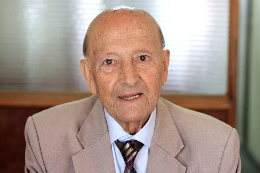 Elderly man faces camera with a slight smile