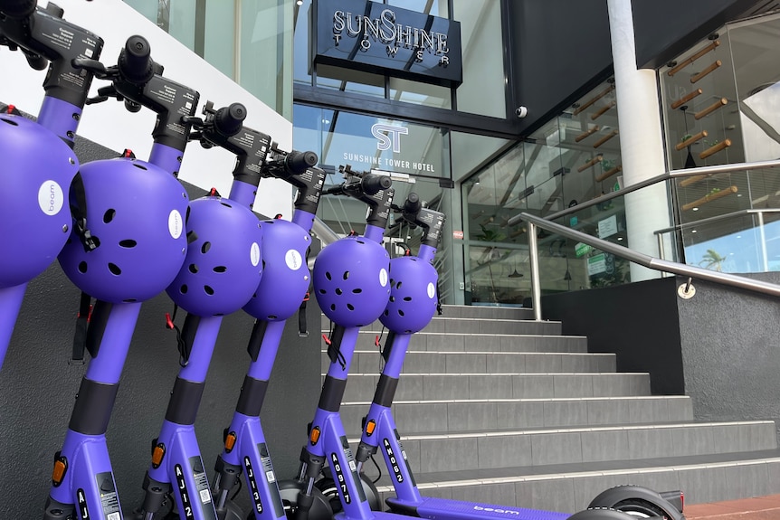Purple scooters lined up against a hotel