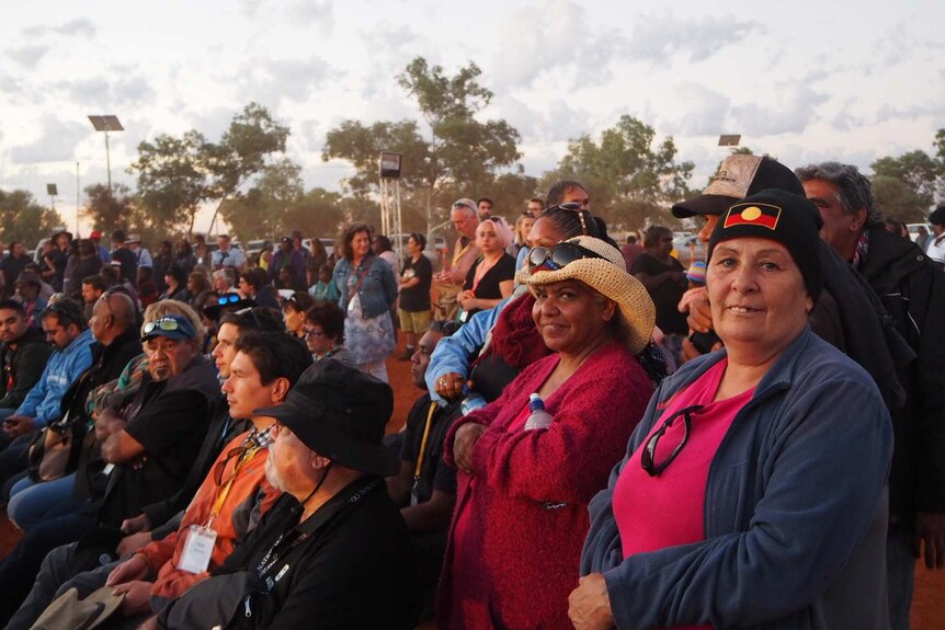A crowd of people watching talks at the constitutional recognition summit in Uluru, two women look at the camera smiling.