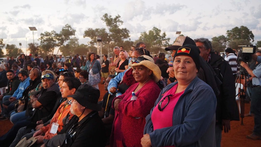 A crowd of people watching talks at the constitutional recognition summit in Uluru, two women look at the camera smiling.