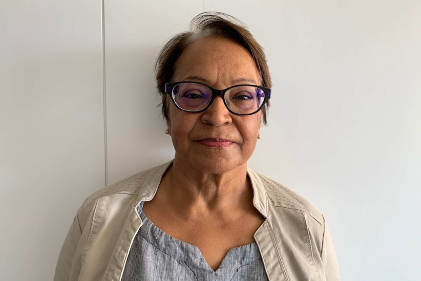 Melbourne author and academic Surjeet Dhanji wearing glasses and standing in front of white wall.