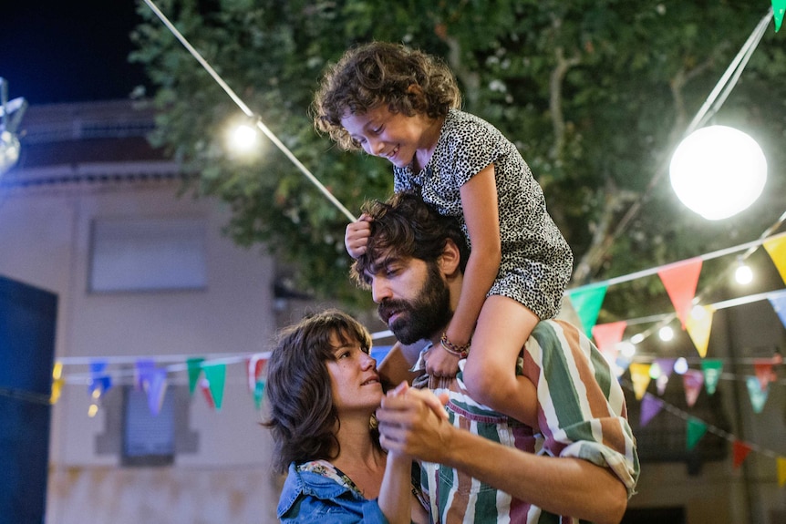 Still from 2017 film Summer 1993 of Bruna Cusi and David Verdaguer dancing outside with Laia Artigas on Verdaguer's shoulders.