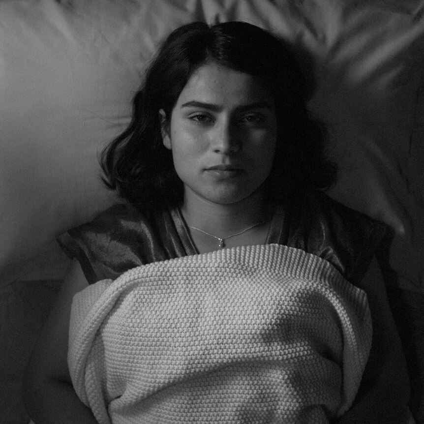 a black and white image of a woman lying in bed