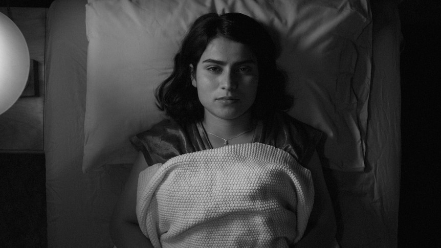 a black and white image of a woman lying in bed