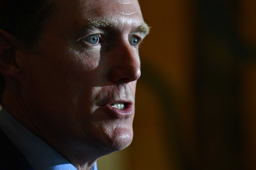 A headshot of Christian Porter close up in partial shadow.