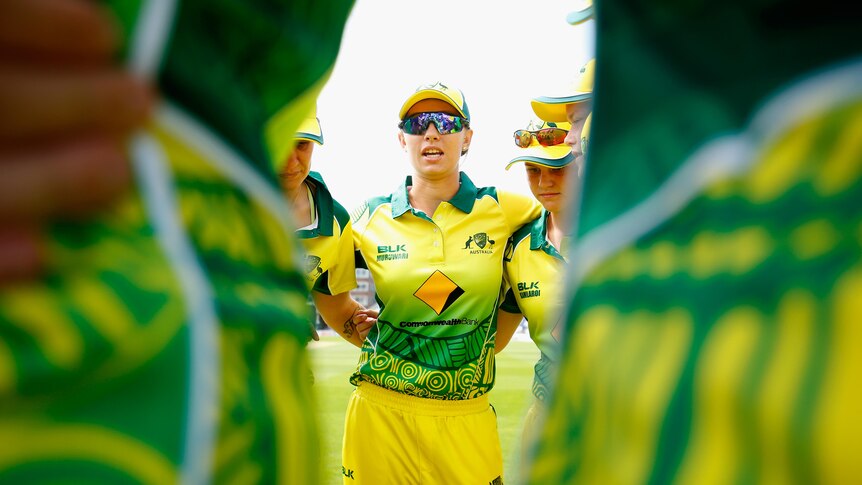 Ashleigh Gardner stands arm in arm with teammates in the Australian Indigenous women's cricket team.