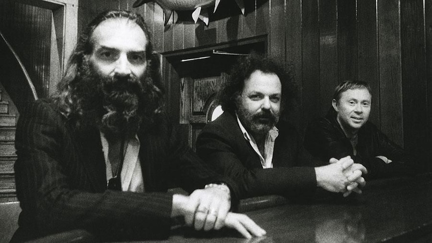 Black and white photo of Dirty Three's Warren Ellis, Jim White, and Mick Turner at a bar