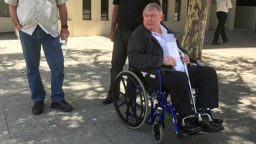 Retired traffic policeman Brian Allen Eddy in a wheelchair outside the Western Australian Coroner's Court in Perth with two men.
