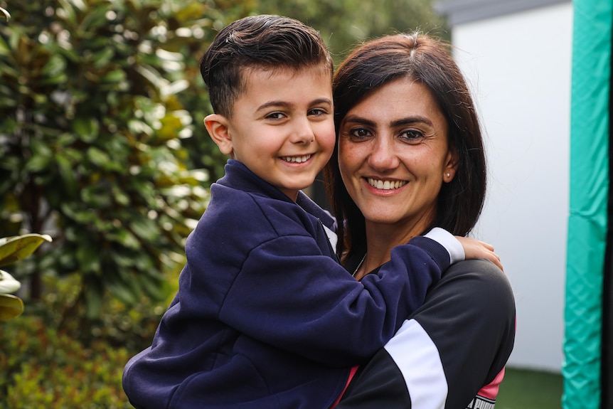 a woman smiling holding a young boy in her arms