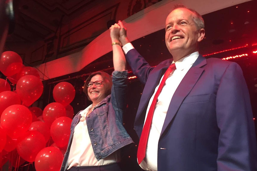 Ged Kearney and Bill Shorten smile and hold their hands in the air.