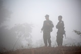 Soldiers of Karen National Union stand guard in a foggy tree lined area.
