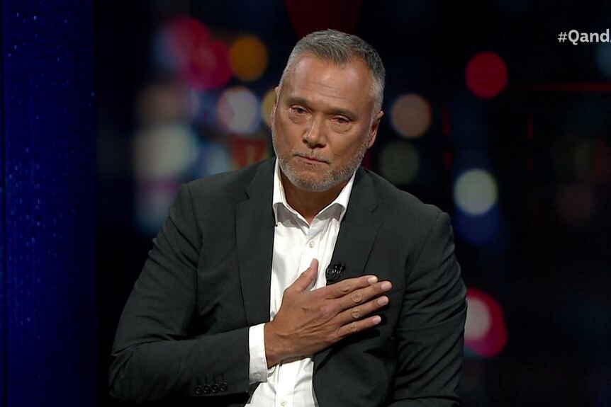 Journalist Stan Grant holds his right hand to his heart on the set of tv show Q and A