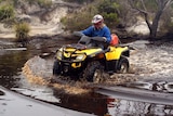 A quad bike is ridden through a river on Tasmania's west coast.