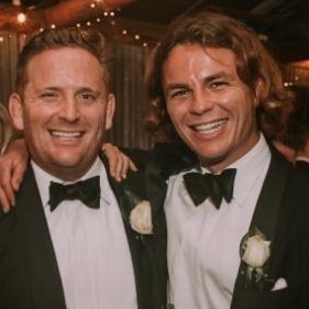 Two young men smile at a formal function.