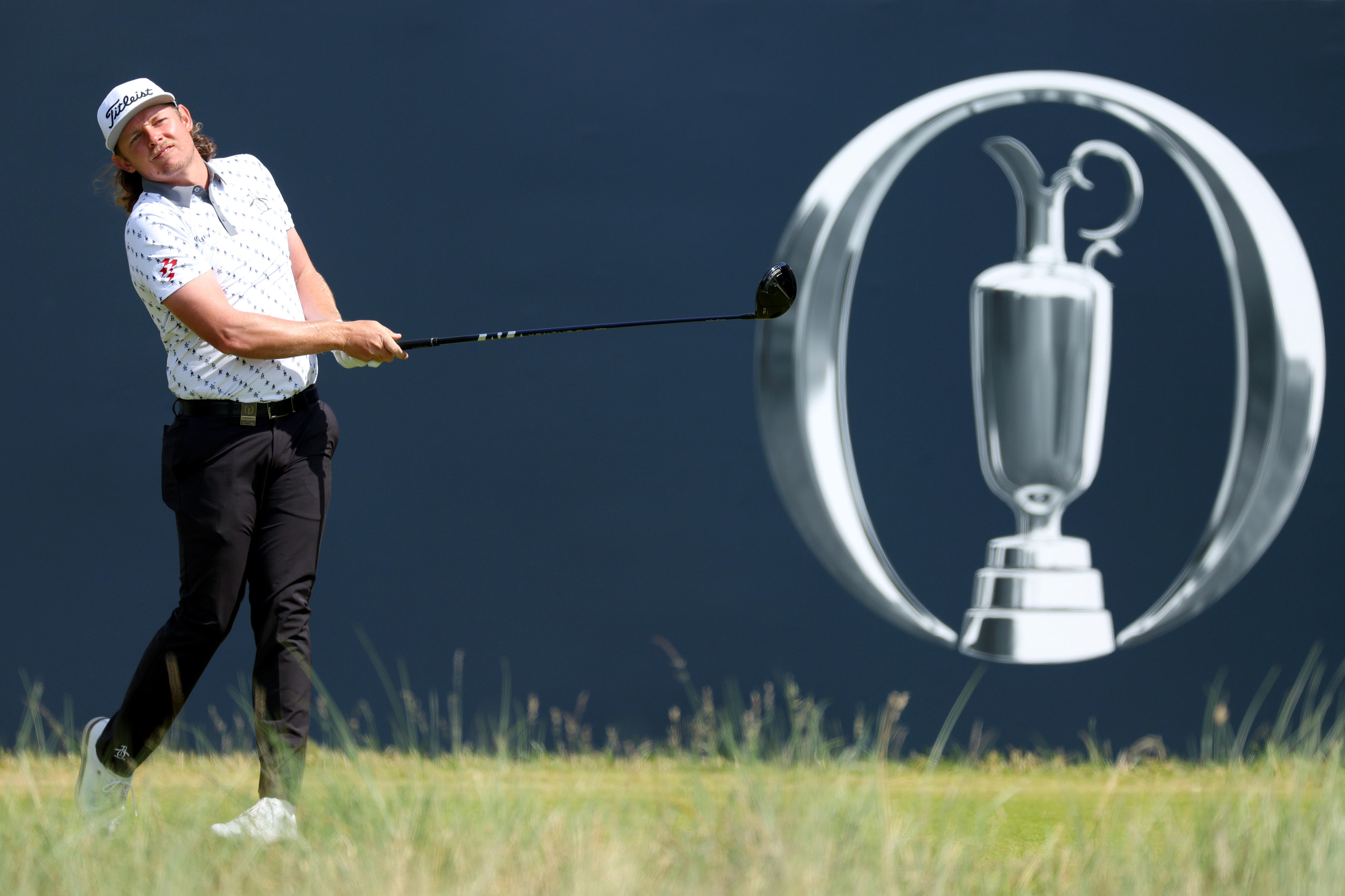 A man looks on after teeing off on a golf course.