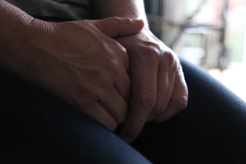 Clasped hands on lap of woman.