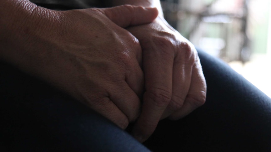 Close-up photo of clasped hands on lap.