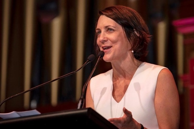 A woman delivers a speech at a podium.