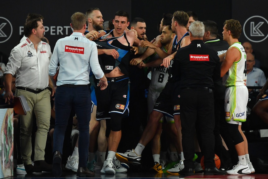 Players and a officials stand closely following a melee in the Melbourne United vs Phoenix NBL game.