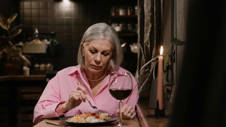 A woman eats dinner at the kitchen table alone