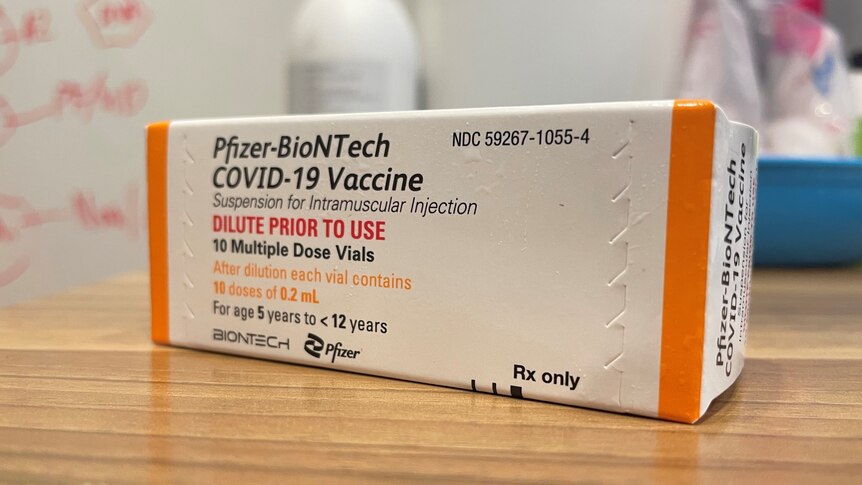 A box of the Pfizer COVID-19 vaccine for children aged 5-12 sits on a wooden table