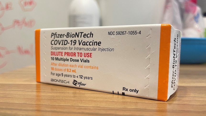 A box of the Pfizer COVID-19 vaccine for children aged 5-12 sits on a wooden table