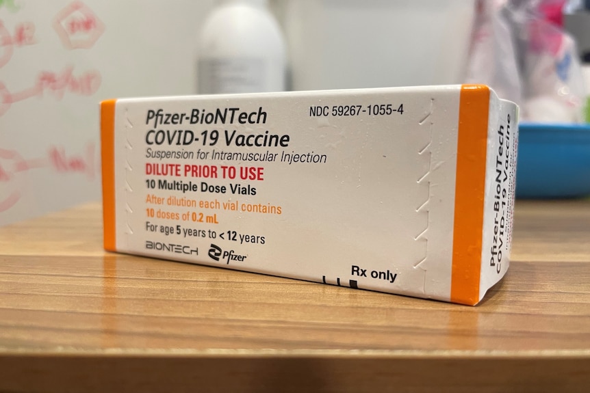 A box of the Pfizer COVID-19 vaccine for children aged 5-12 sits on a wooden table