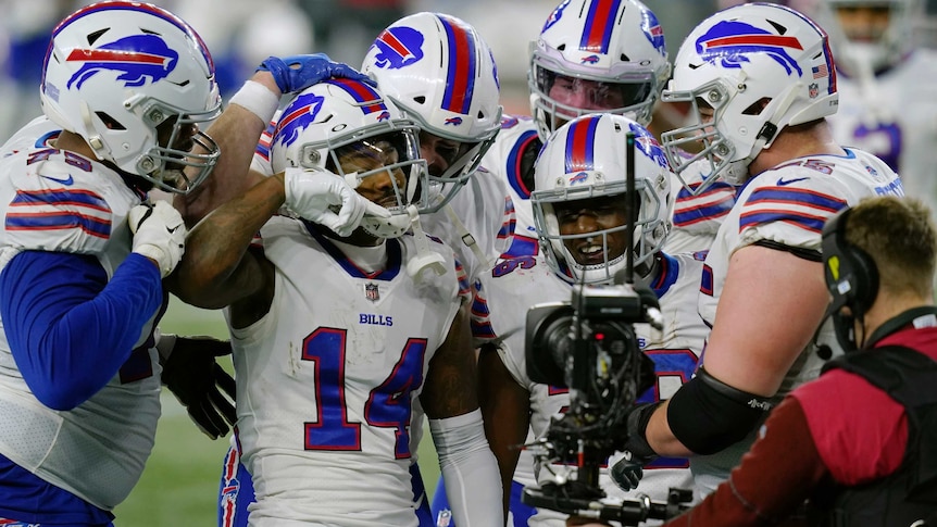 Stefon Diggs celebrates with a group of Buffalo Bills teammates in front of a camera