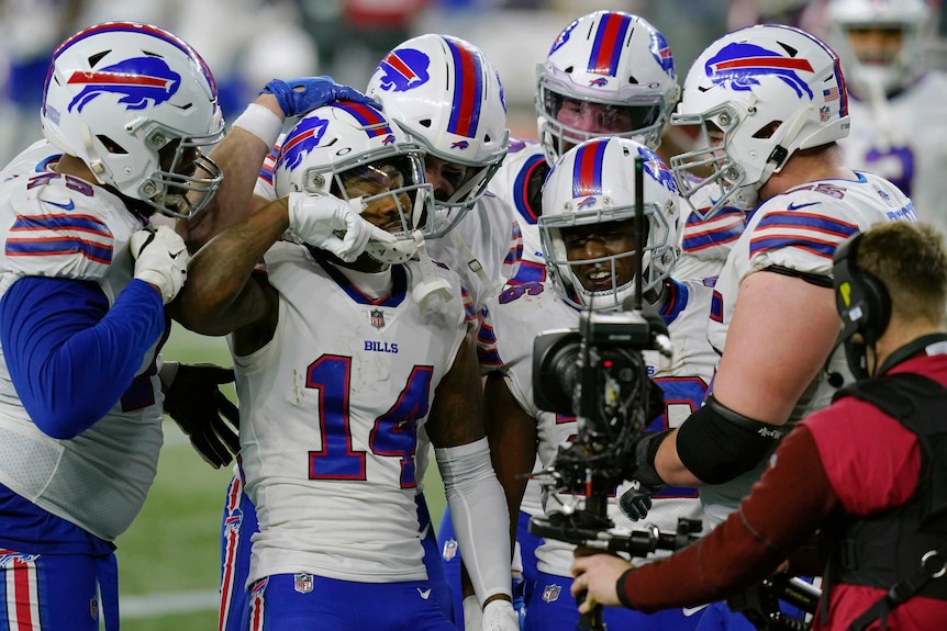 Stefon Diggs celebrates with a group of Buffalo Bills teammates in front of a camera