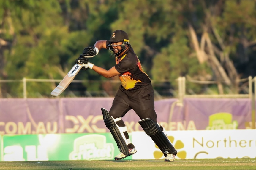 A PNG cricketer gets on the front foot and plays a drive shot during a cricket match.