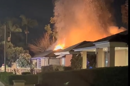A house with flames leaping behind it