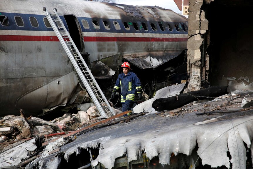 A rescue worker walks past rubble and plane wreckage.