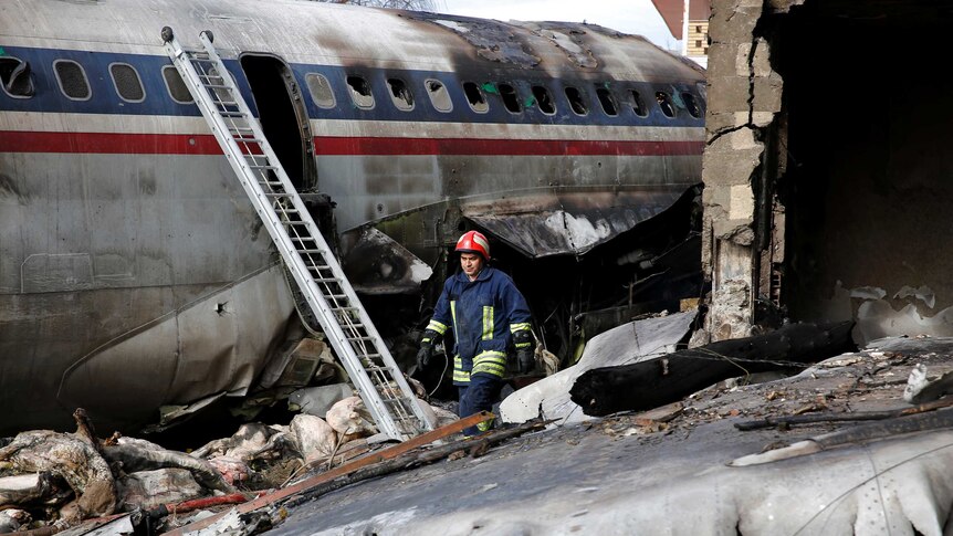 A rescue worker walks past rubble and plane wreckage.