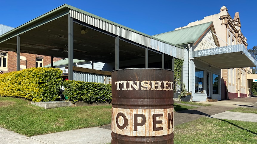 Rustic building with a barrel painted with the name Tinshed Brewery, Open