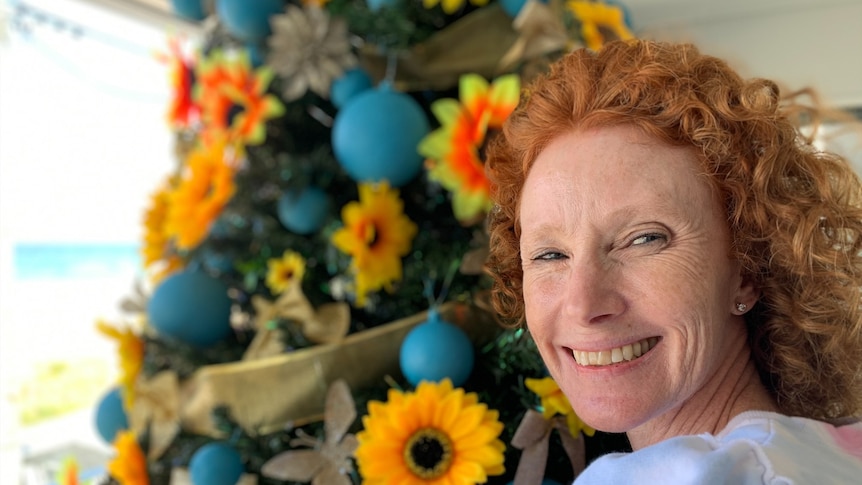 Fiona Sillar standing beside her huge Christmas tree decorated with sunflowers and blue baubles