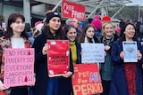 On an overcast day, you view a group of women holding placards advocating for universal period products.