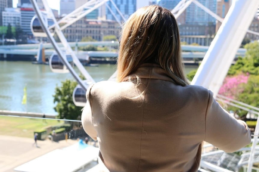 The back of a blonde woman standing looking at Brisbane city, who wished to remain anonymous.