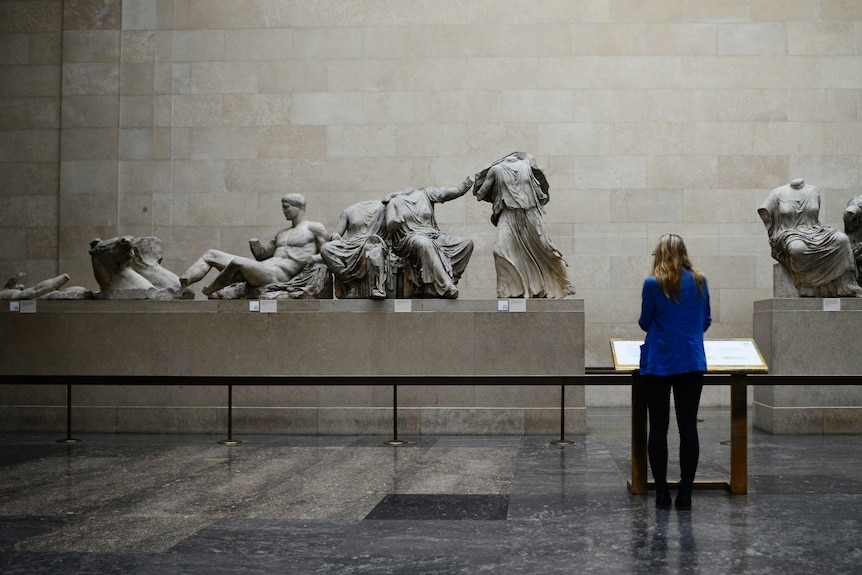 A woman looks at the Parthenon Marbles, a collection of stone objects.